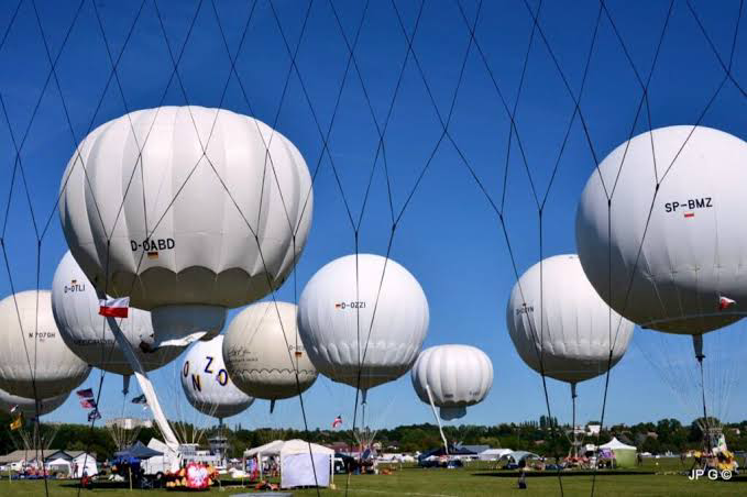 Gordon Bennett Cup gas balloons tethered under anti-collision netting at a launch field