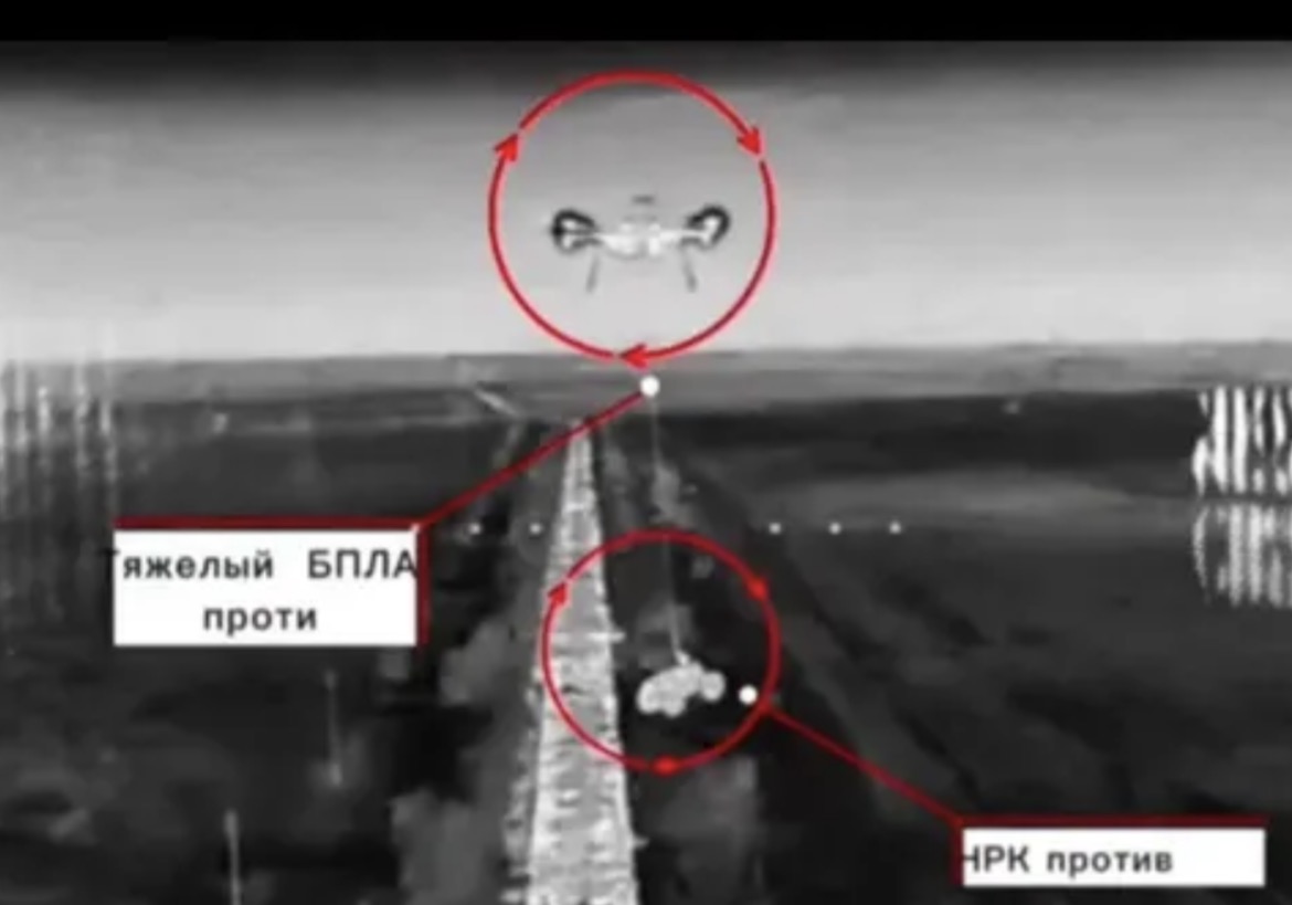 Thermal footage showing a heavy-lift drone circling above a ground robot on a road