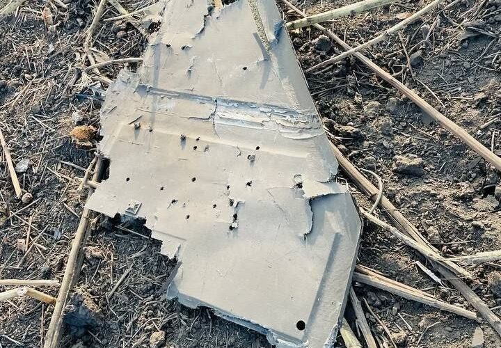 A grey composite wing panel from the crashed drone lying in the burnt field near Mihăileni Vechi, perforated with shrapnel holes, September 2026